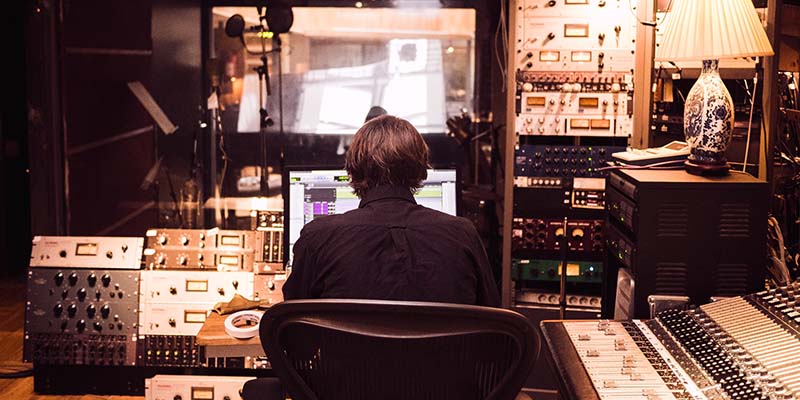 Conservación y archivo de los medios de comunicación_equipos de radio El conservador de medios y archivero se sienta en una sala rodeado de equipos de audio