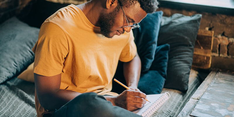 side-hustles-man-writing Un autónomo anota sus ideas creativas en su cuaderno