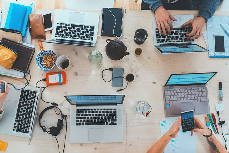 travailler-avec-des-clients-équipe-busy Une équipe de monteurs vidéo travaille sur une table commune.